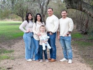 Family of five wearing coordinated cream and white outfits poses together outdoors.