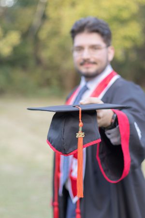 A graduation cap with a red tassel shown in a progression of motion blur against a blurred outdoor background.