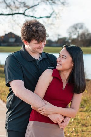 A couple shares tender moments together outdoors by a lake on a sunny autumn day.