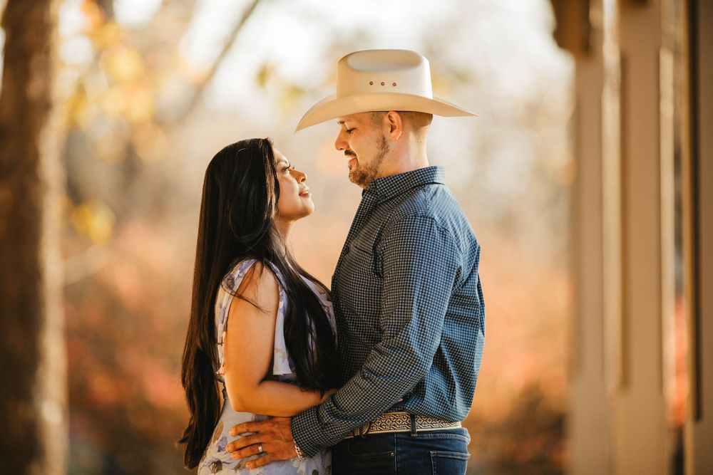 Romantic couple embracing in warm autumn light with cowboy hat outdoors.