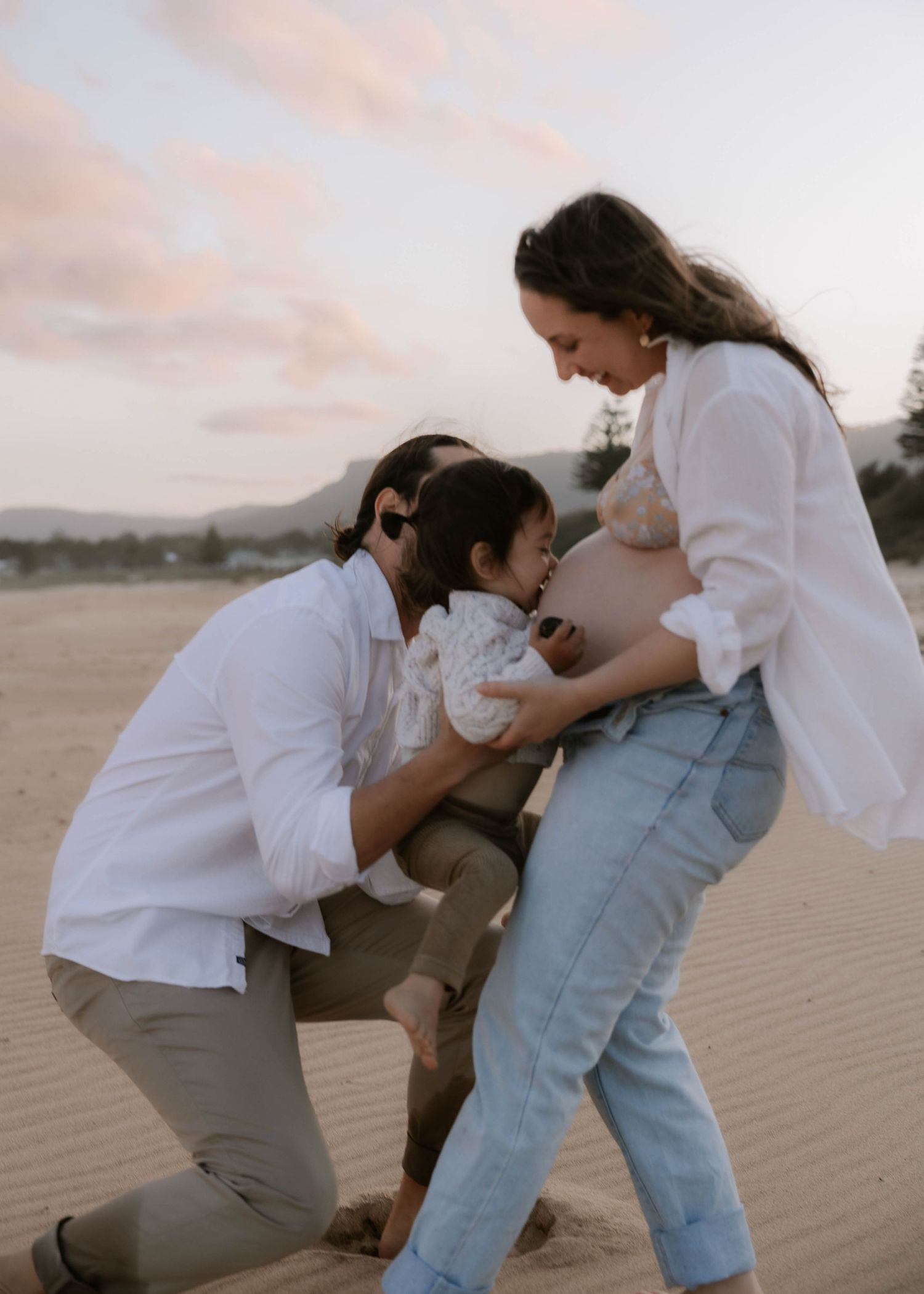 Maternity family photoshoot at Bulli Beach – Toddler kissing pregnant mum’s belly. Natural Wollongong photography by Lovers and Bubs.