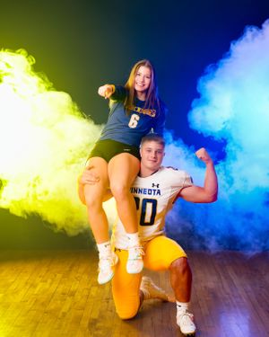Minnesota Vikings football player #20 kneels while volleyball player #6 sits on his shoulder flexing.