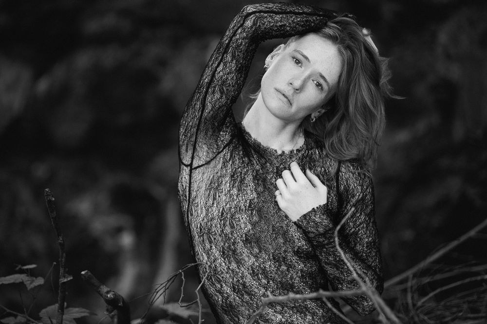 Black and white portrait of woman in lace dress with dramatic lighting.
