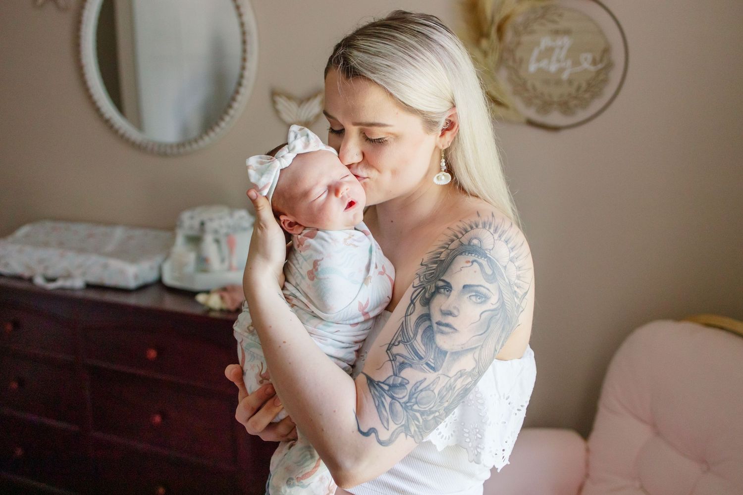 A couple in casual sweaters cuddles with their infant on a couch in an intimate family moment.
