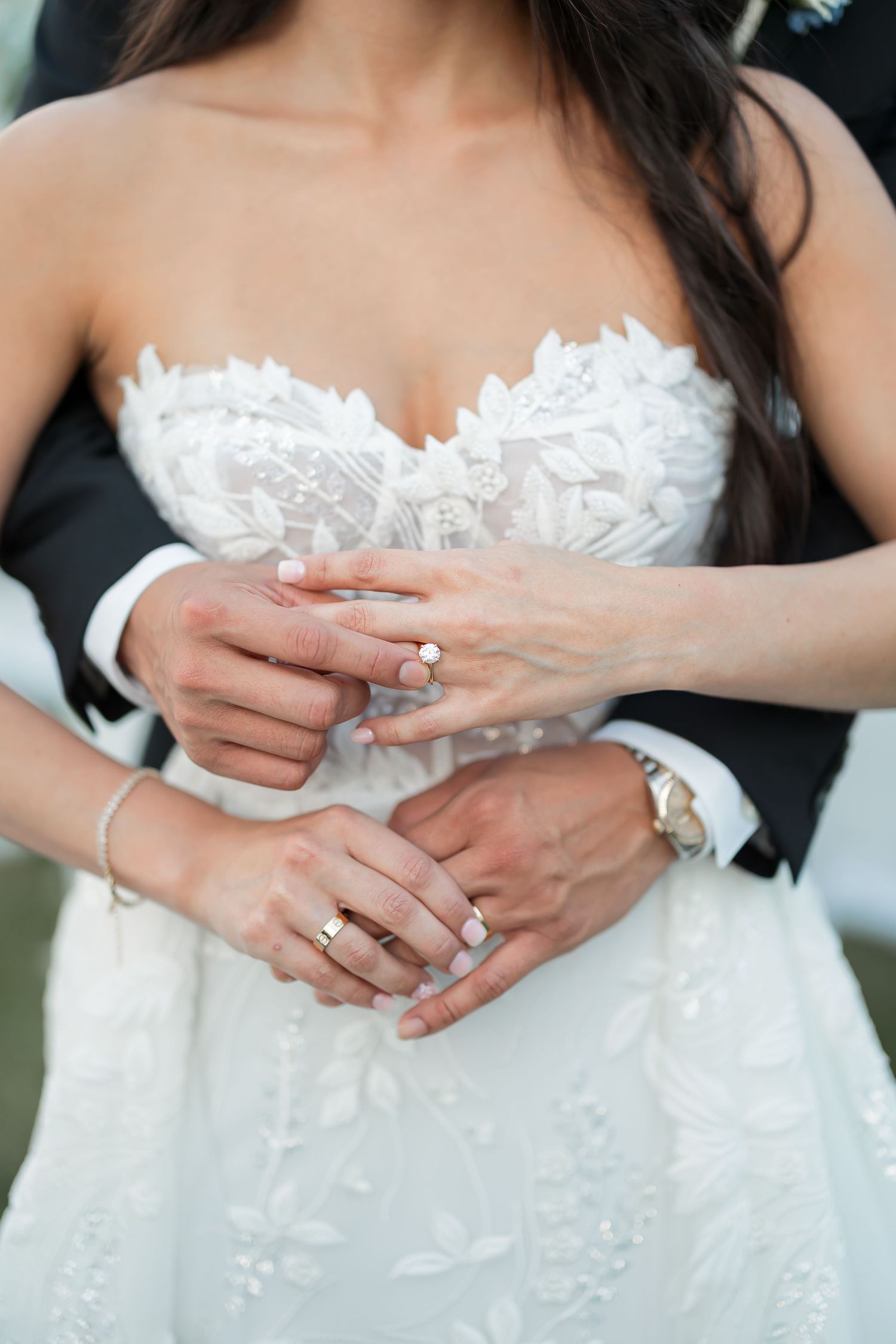 Close-up of a woman's hands with a wedding ring as she holds her dress.