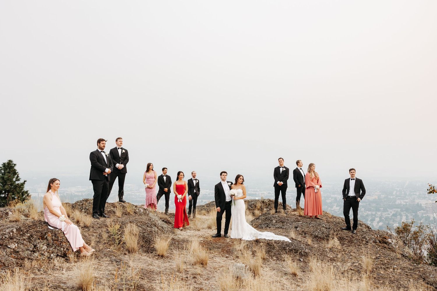A wedding party stands on a scenic cliff overlooking the ocean during a coastal outdoor ceremony.