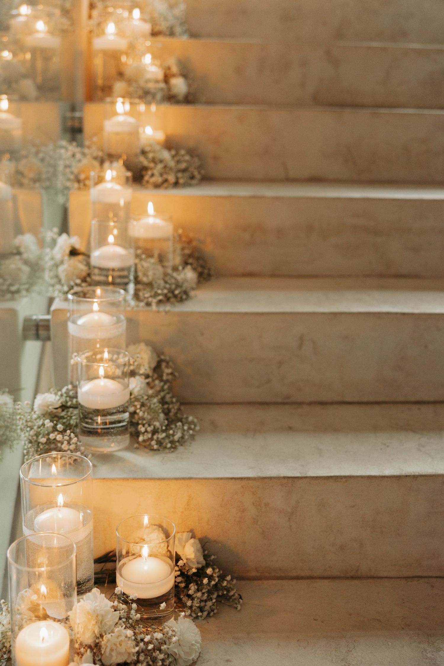 Romantic stone staircase decorated with glowing candles in glass jars and delicate baby's breath flowers.