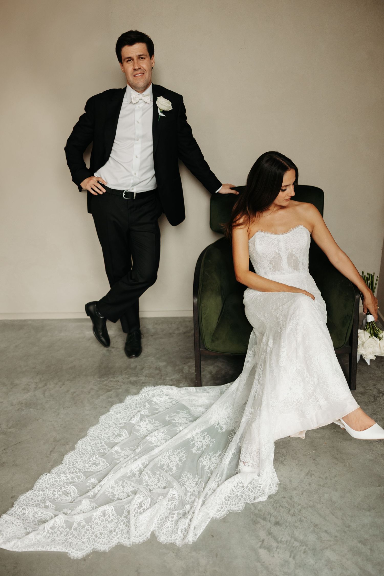 A series of wedding photos showing a bride in a lace gown and groom in a dark suit posing together on a grey floor.