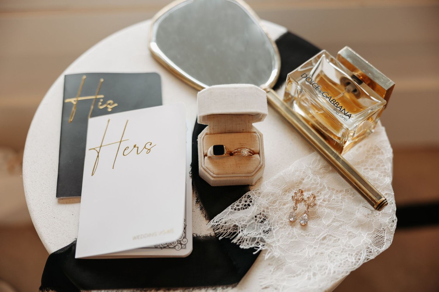 Elegant wedding details including perfume bottles, name cards, and delicate lace accessories on a neutral surface.