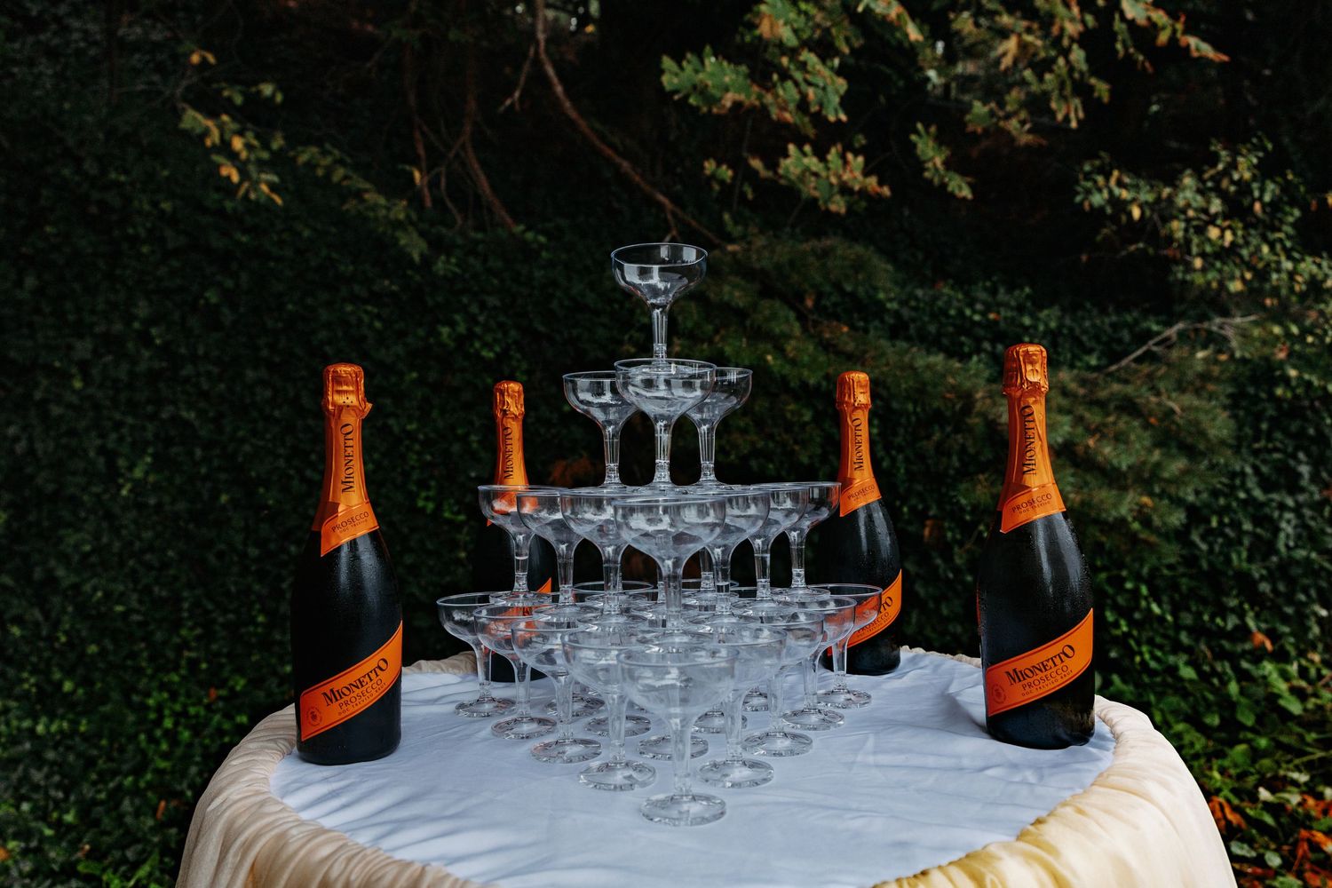 Champagne tower being carefully constructed with glasses and orange bottles of Veuve Clicquot champagne.