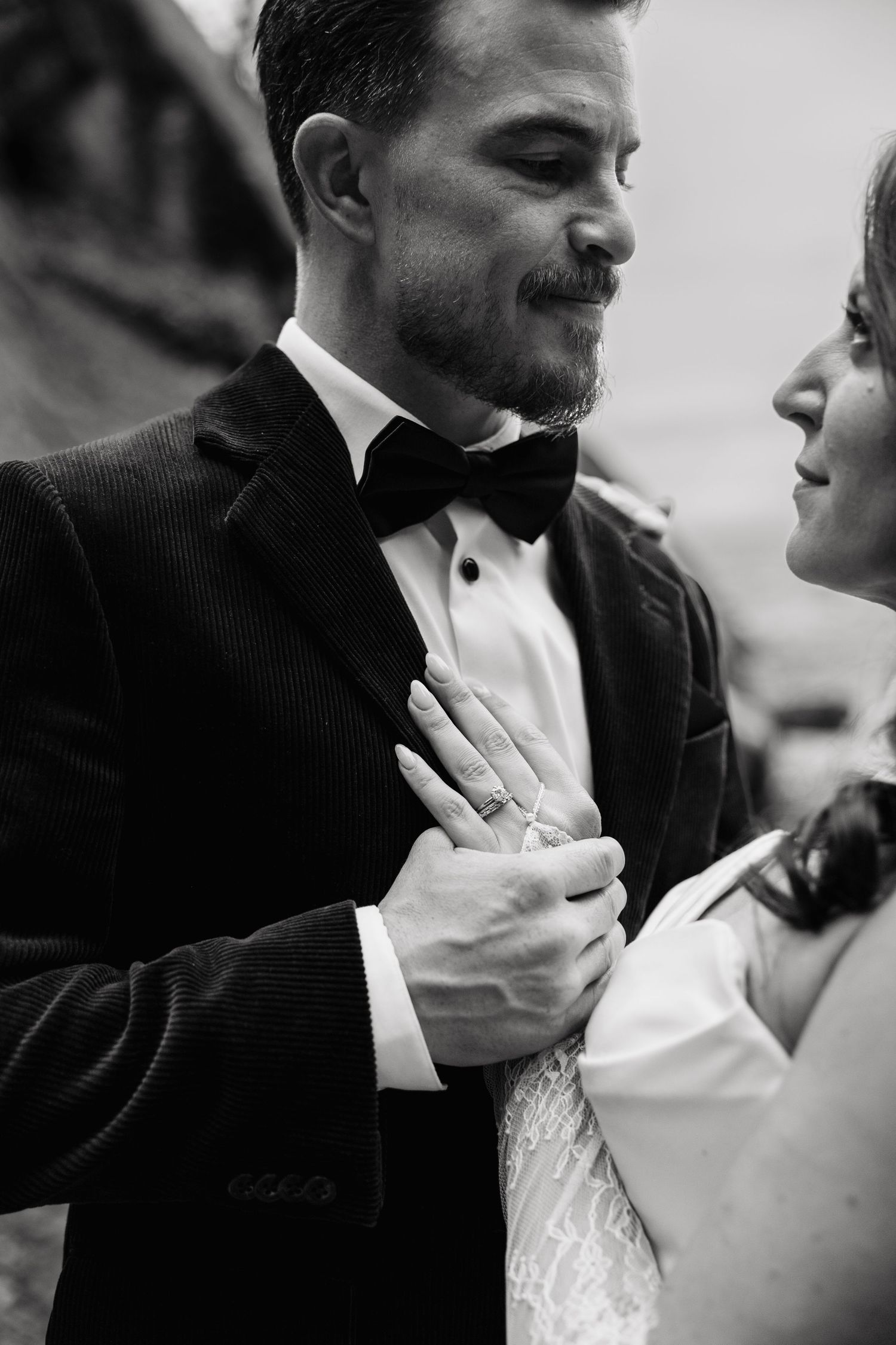 A tender black and white moment between newlyweds as they share an intimate embrace, showing off her engagement ring.