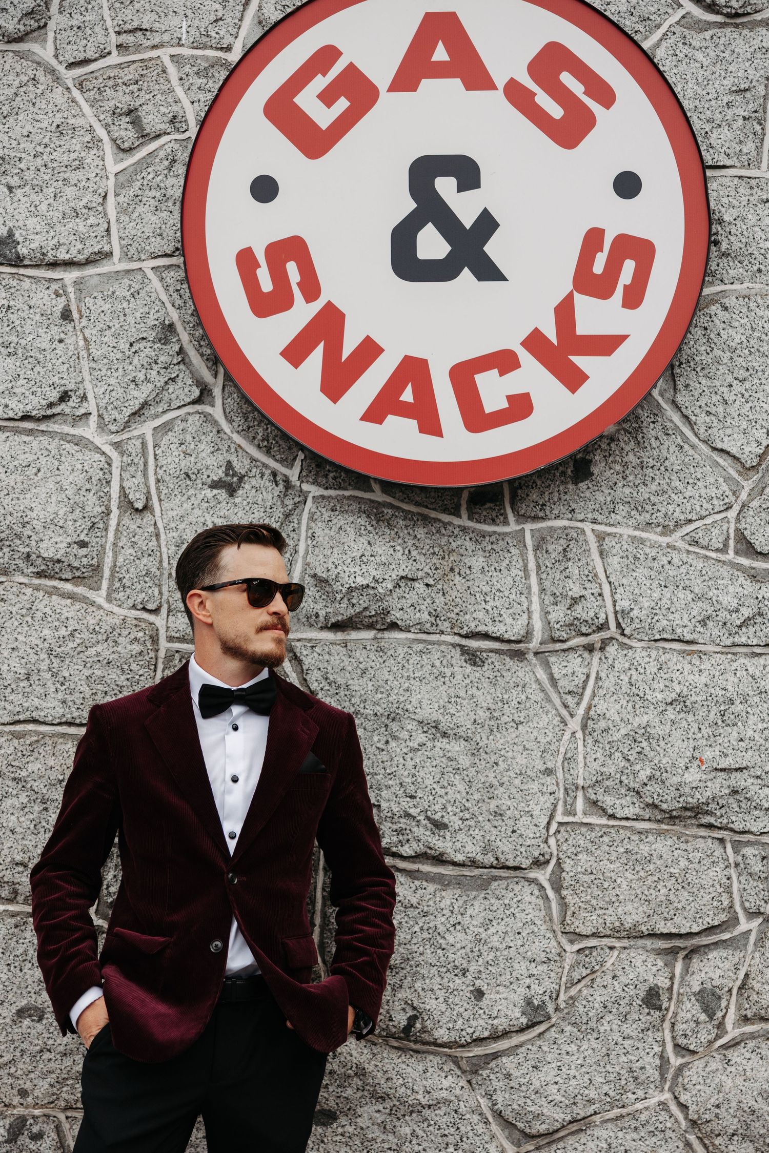 A series of five photos showing a person in a suit and sunglasses posing against a stone wall with red circular signs.