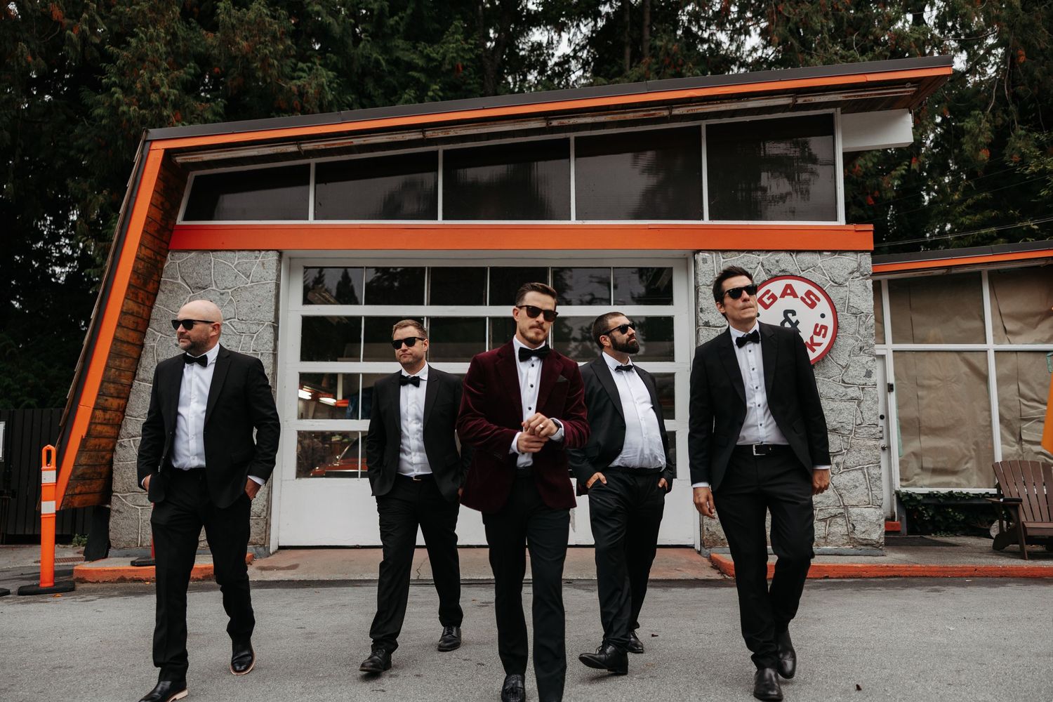 A group in formal black attire walking together outdoors in a casual synchronized manner.
