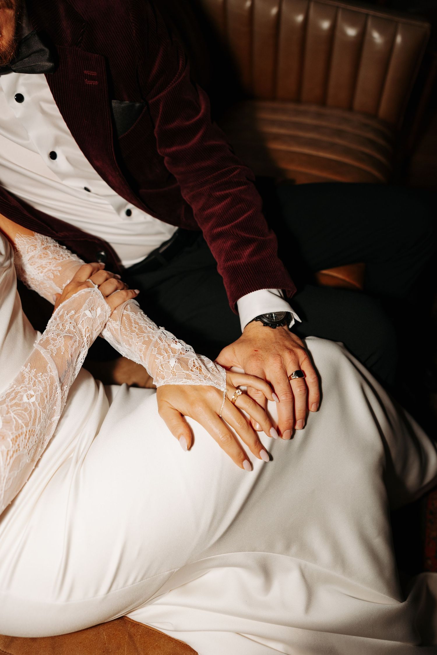 Close-up view of hands resting on white lace wedding dress fabric.