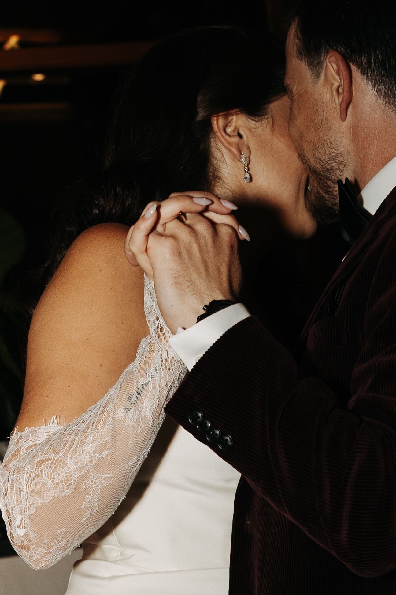 Close-up shots of a romantic wedding kiss between newlyweds, with the bride wearing delicate white lace sleeves.