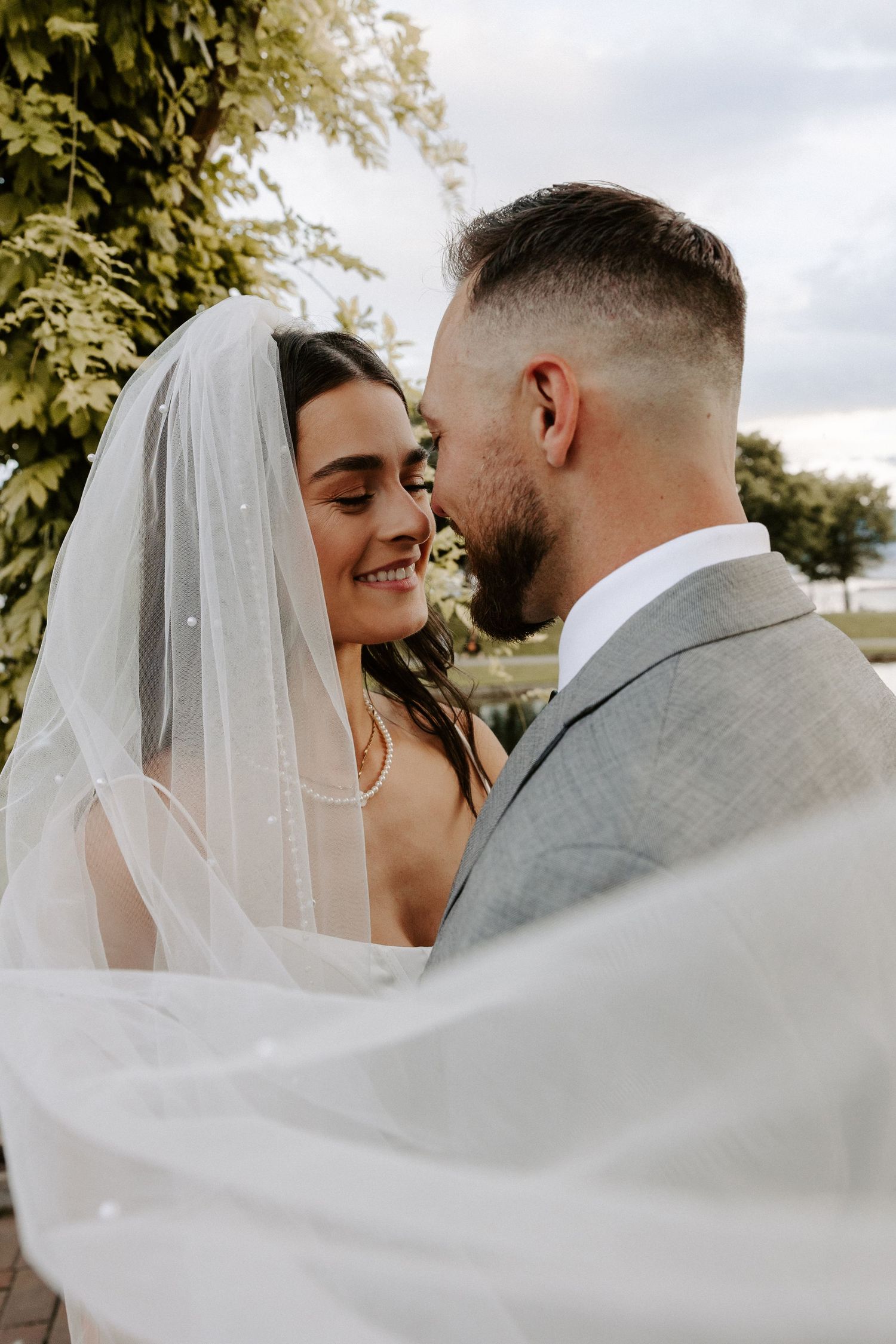 A romantic newlywed couple shares intimate moments as the bride's veil flows dramatically in the wind.