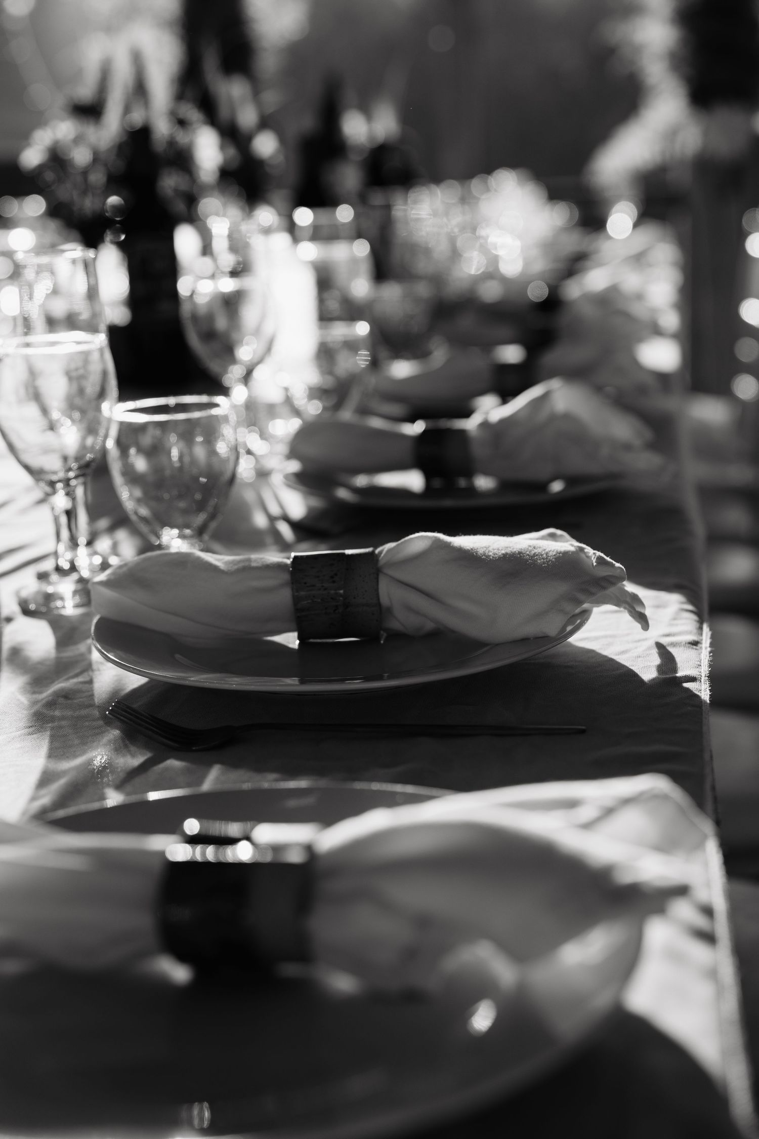 Elegant black and white table setting with folded napkins, wine glasses and plates at a formal dinner event.