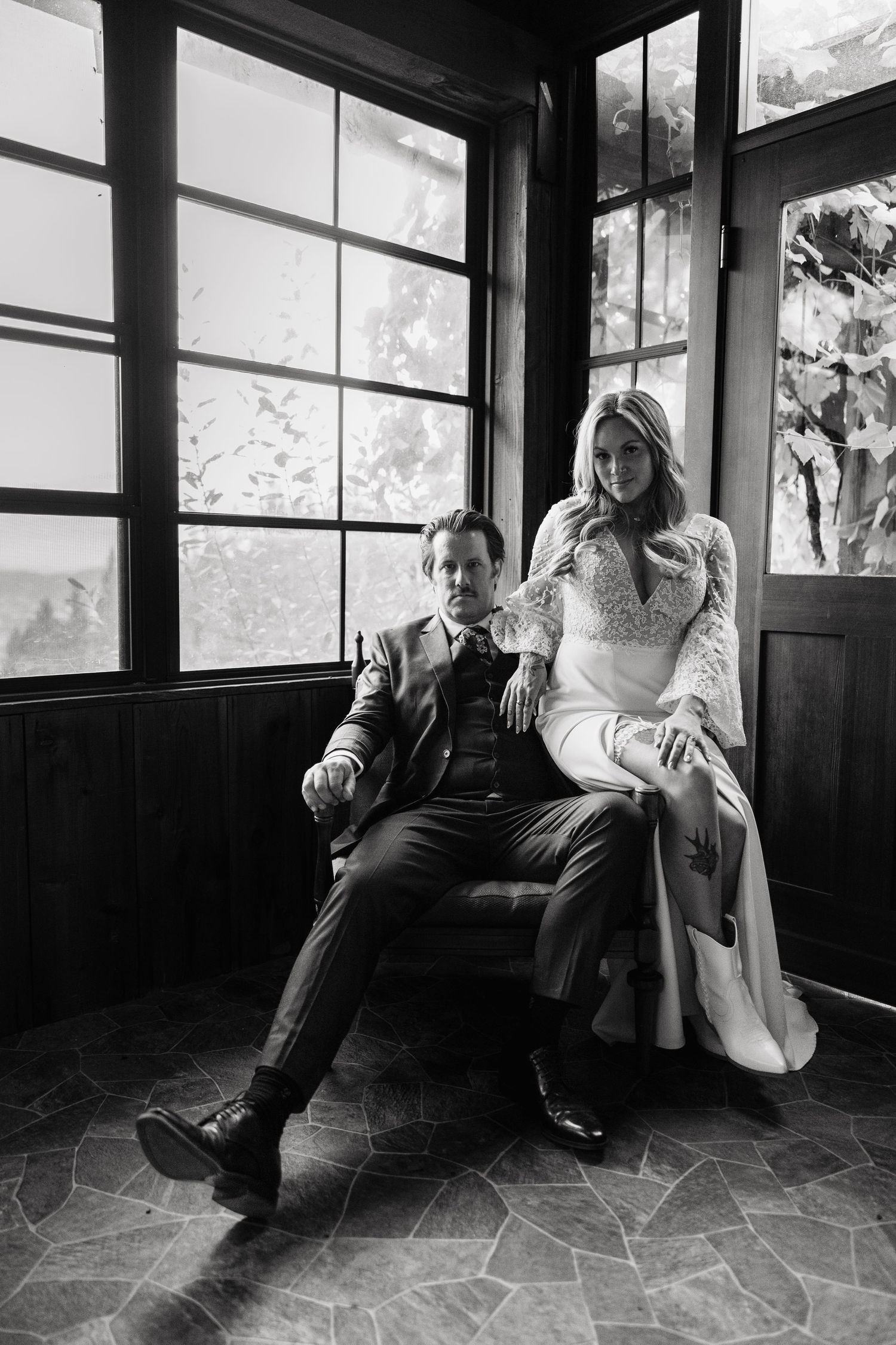 A black and white series of artistic portraits showing a couple lounging in a sunlit room with large windows.