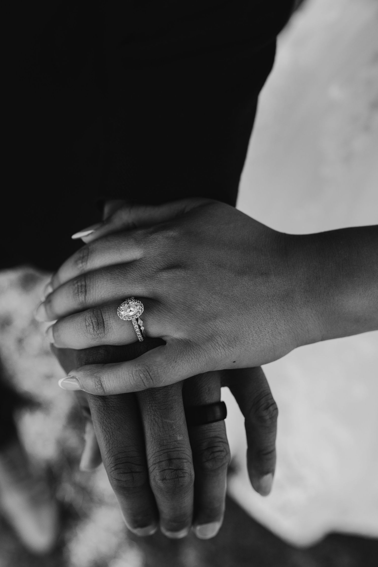 Close-up of hands wearing wedding rings in black and white photography.