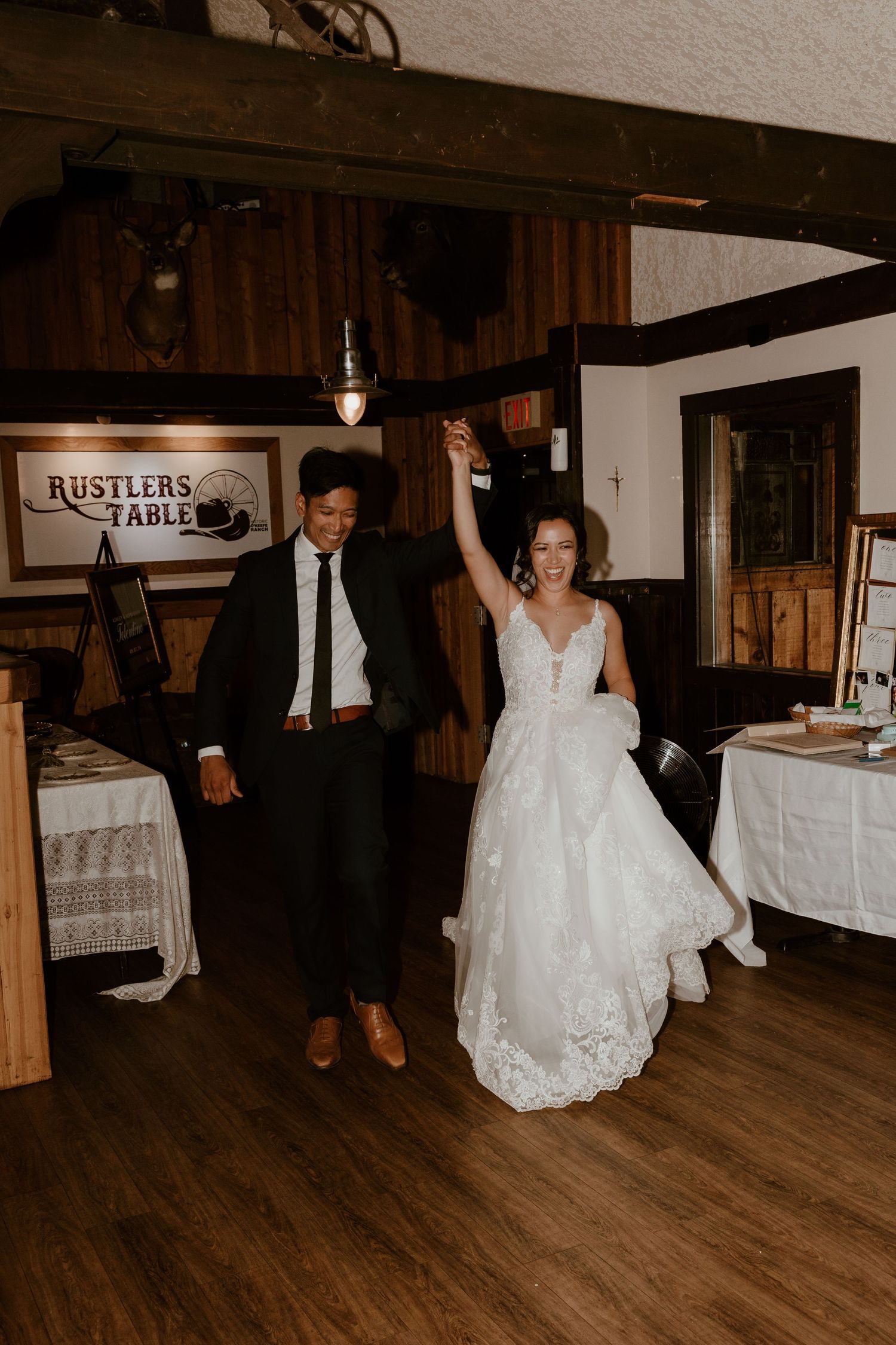 Couple dancing joyfully at rustic wedding reception venue with wooden decor.
