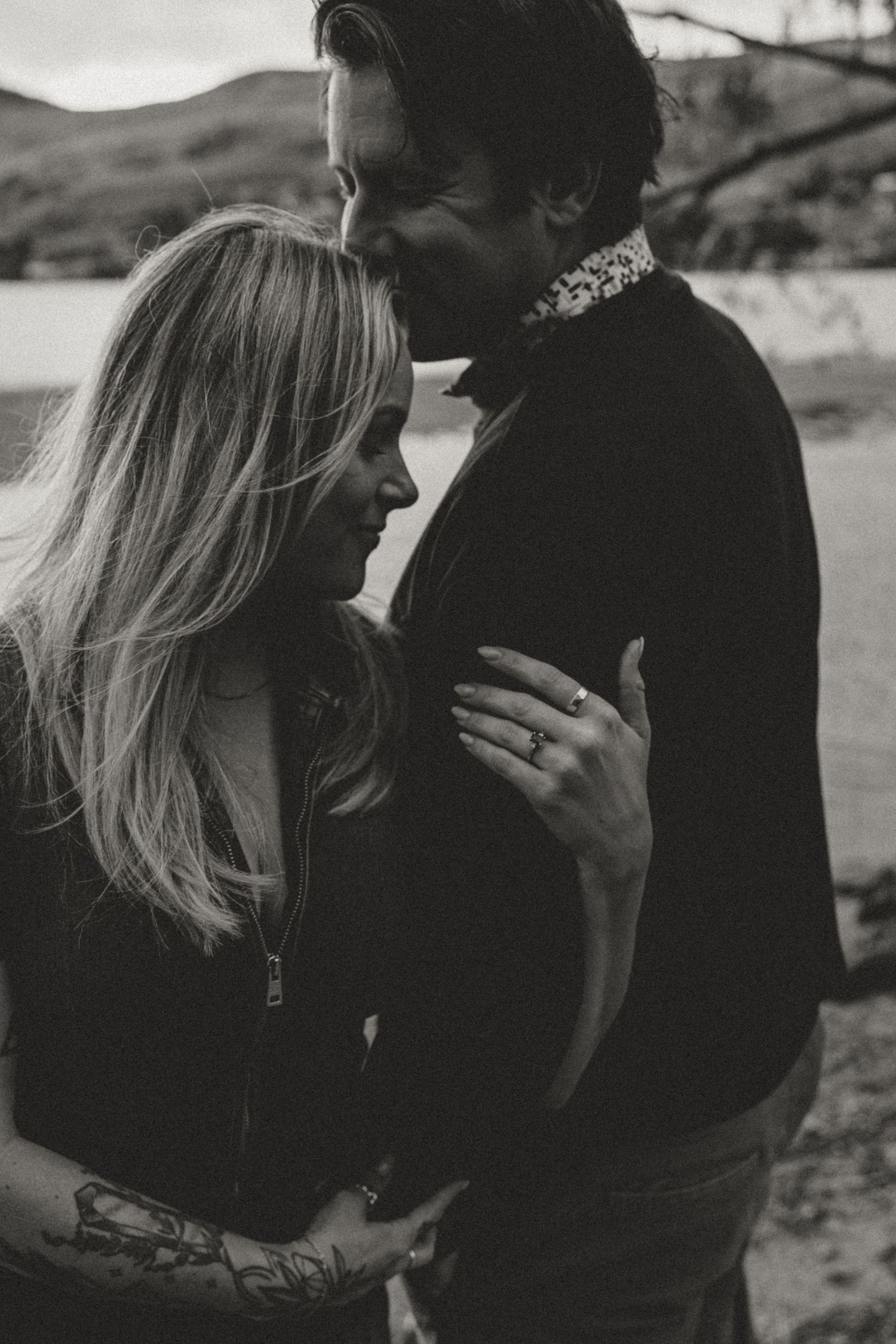 Intimate black and white portrait of a romantic couple embracing outdoors.