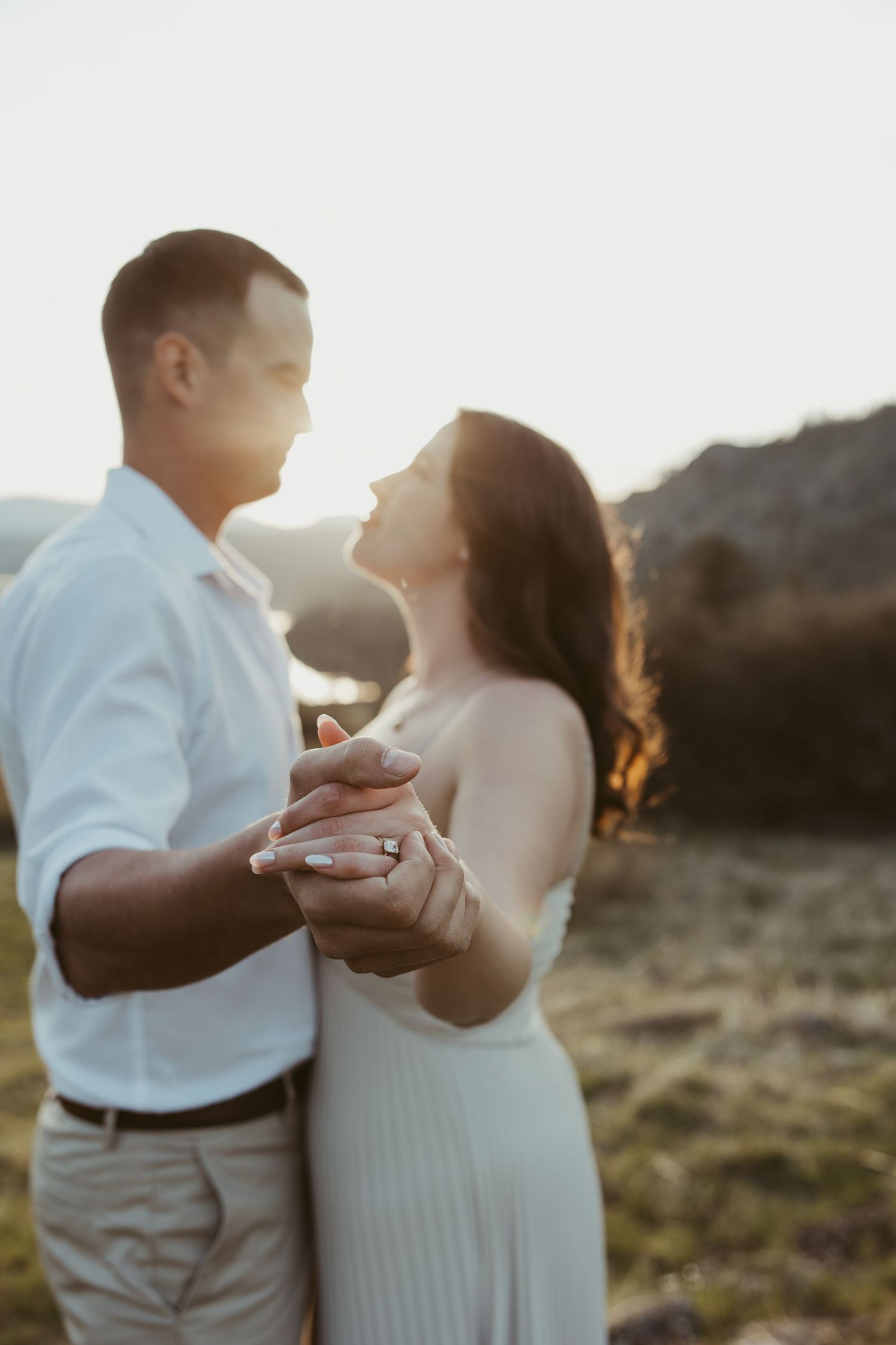 A tender moment captured between a couple dancing outdoors with mountains in the background at golden hour.
