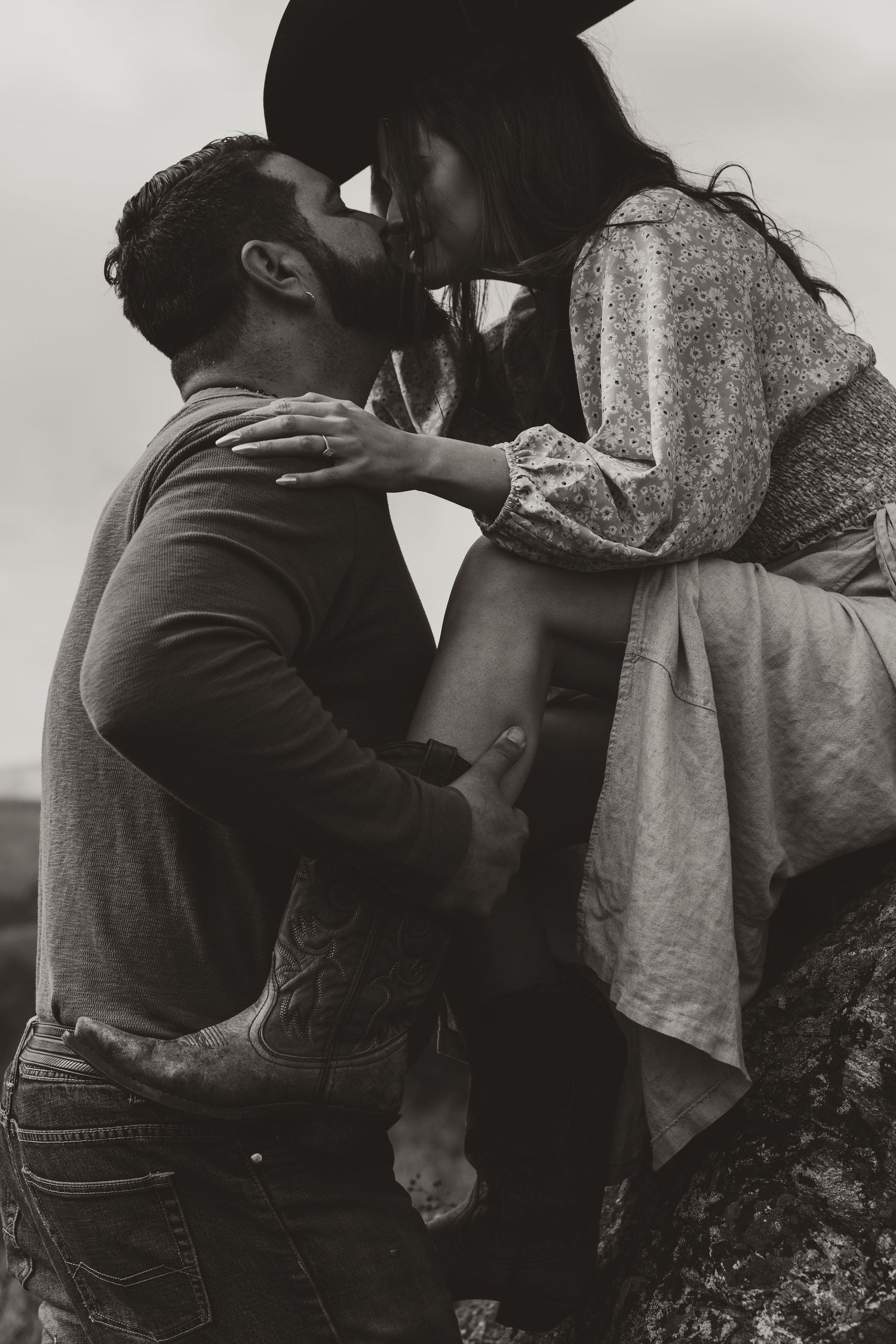 An intimate black and white portrait of a couple sharing a tender moment outdoors.