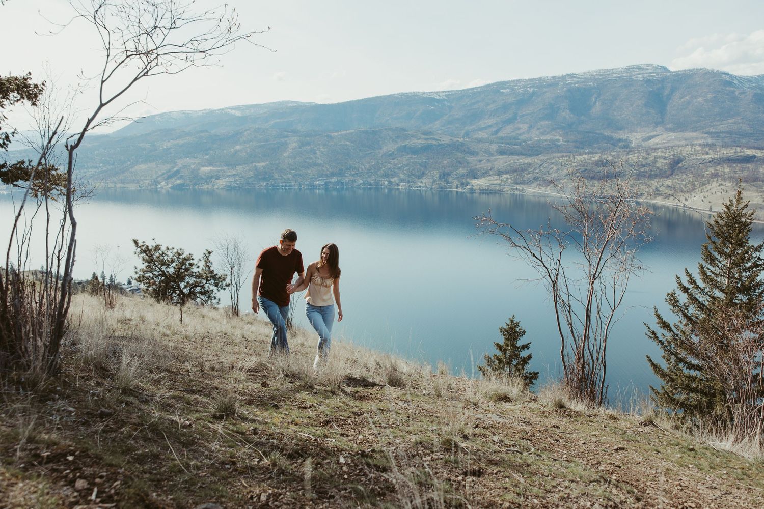 Couple walking along scenic mountain trail overlooking pristine lake.