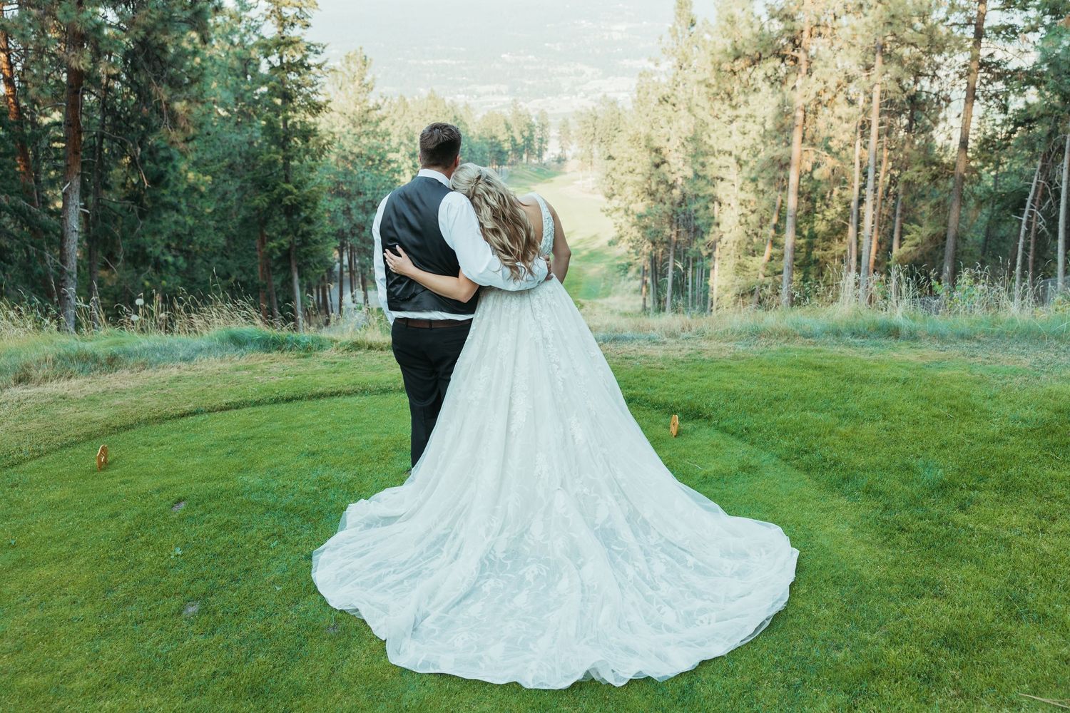Newlyweds overlook a scenic mountain vista in elegant wedding attire.