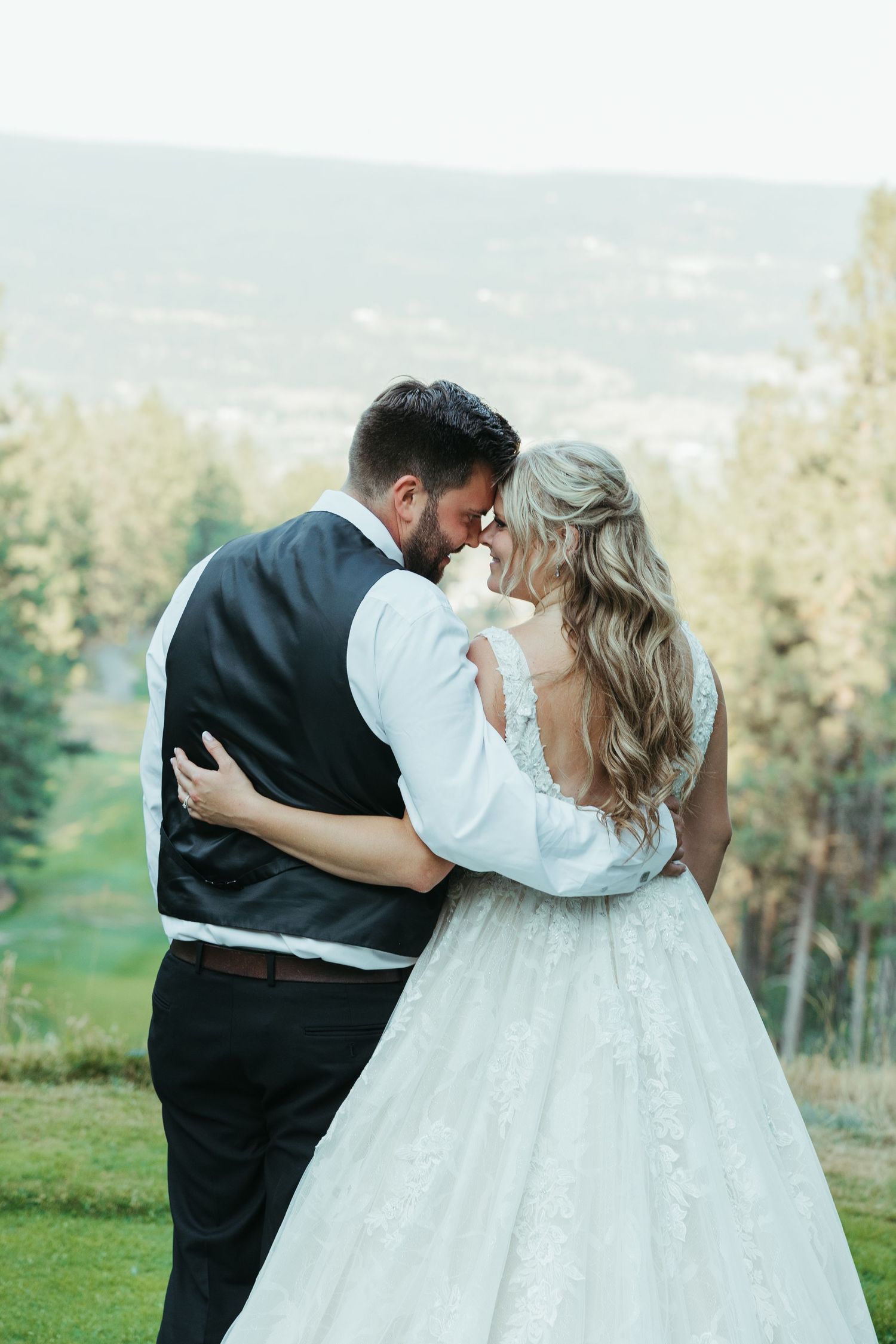 A romantic moment between newlyweds with mountains in the background.