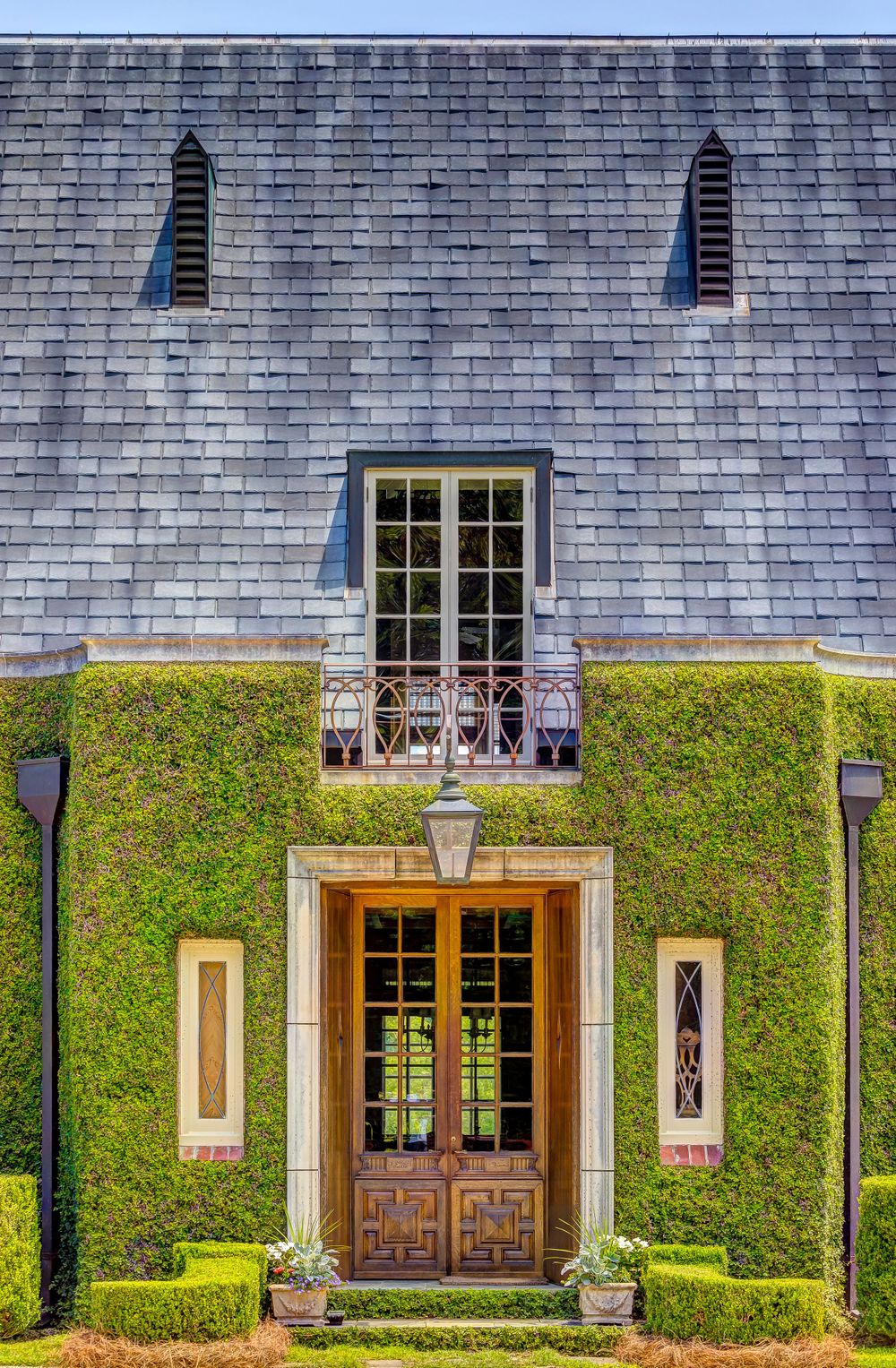 Elegant ivy-covered building entrance with double wooden doors and slate roof.
