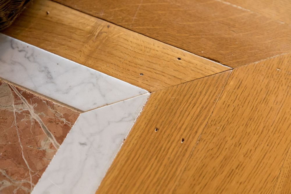 Detail of wood flooring meeting marble corner inlay in luxurious interior.