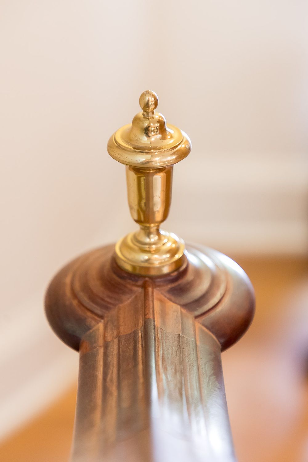 Close-up of ornate brass finial detail on wooden furniture.