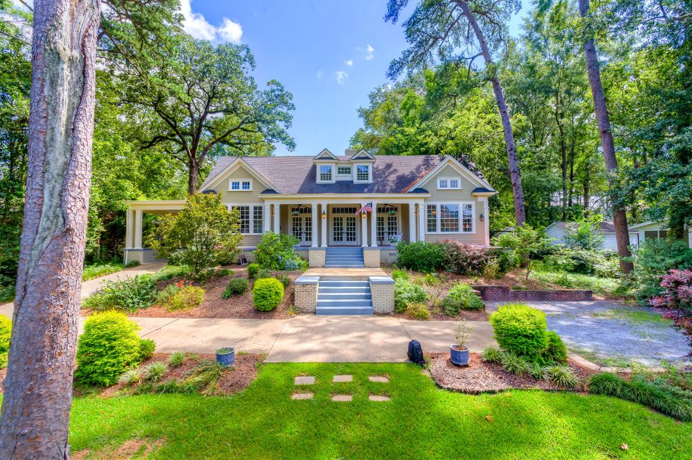 Charming craftsman style home with manicured landscaping and stone pathway leading to covered front porch.