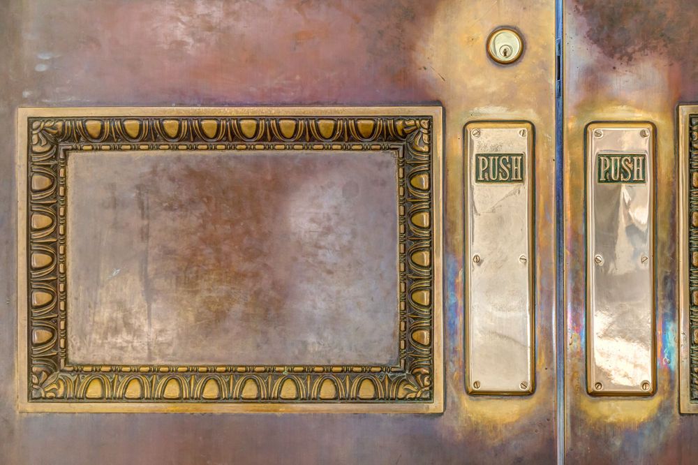 Vintage ornate brass frame and door hardware with weathered patina finish.