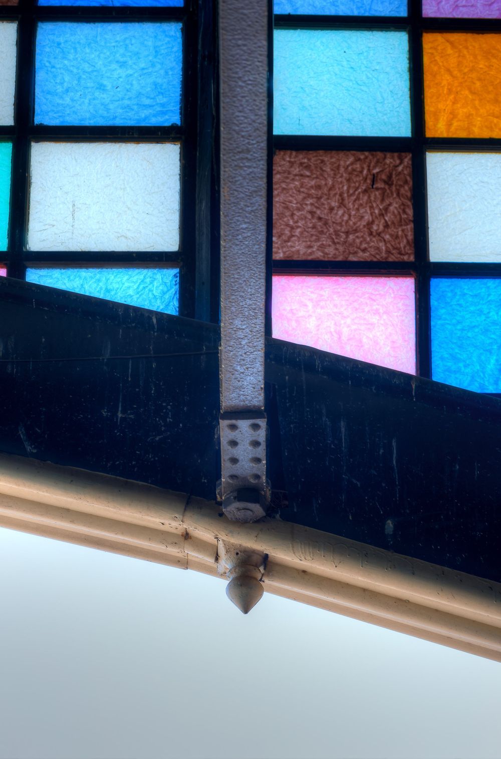 Close-up detail of colorful stained glass window panels in blue, pink, and orange hues.