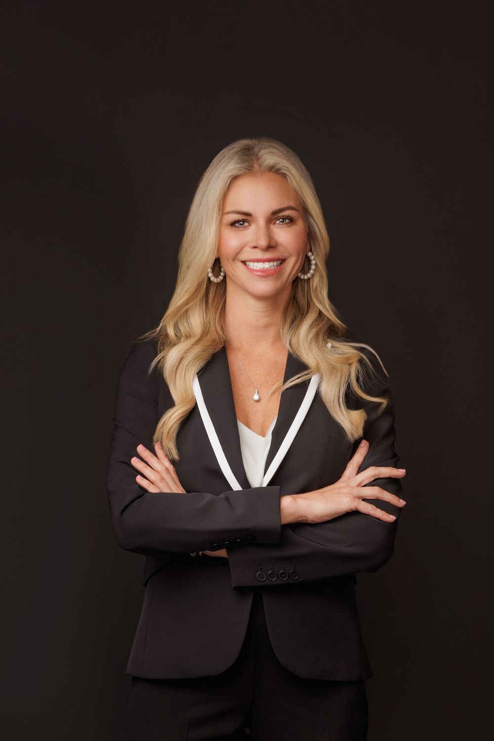 Professional headshot series of a person in a black blazer against dark background showing different poses and expressions.