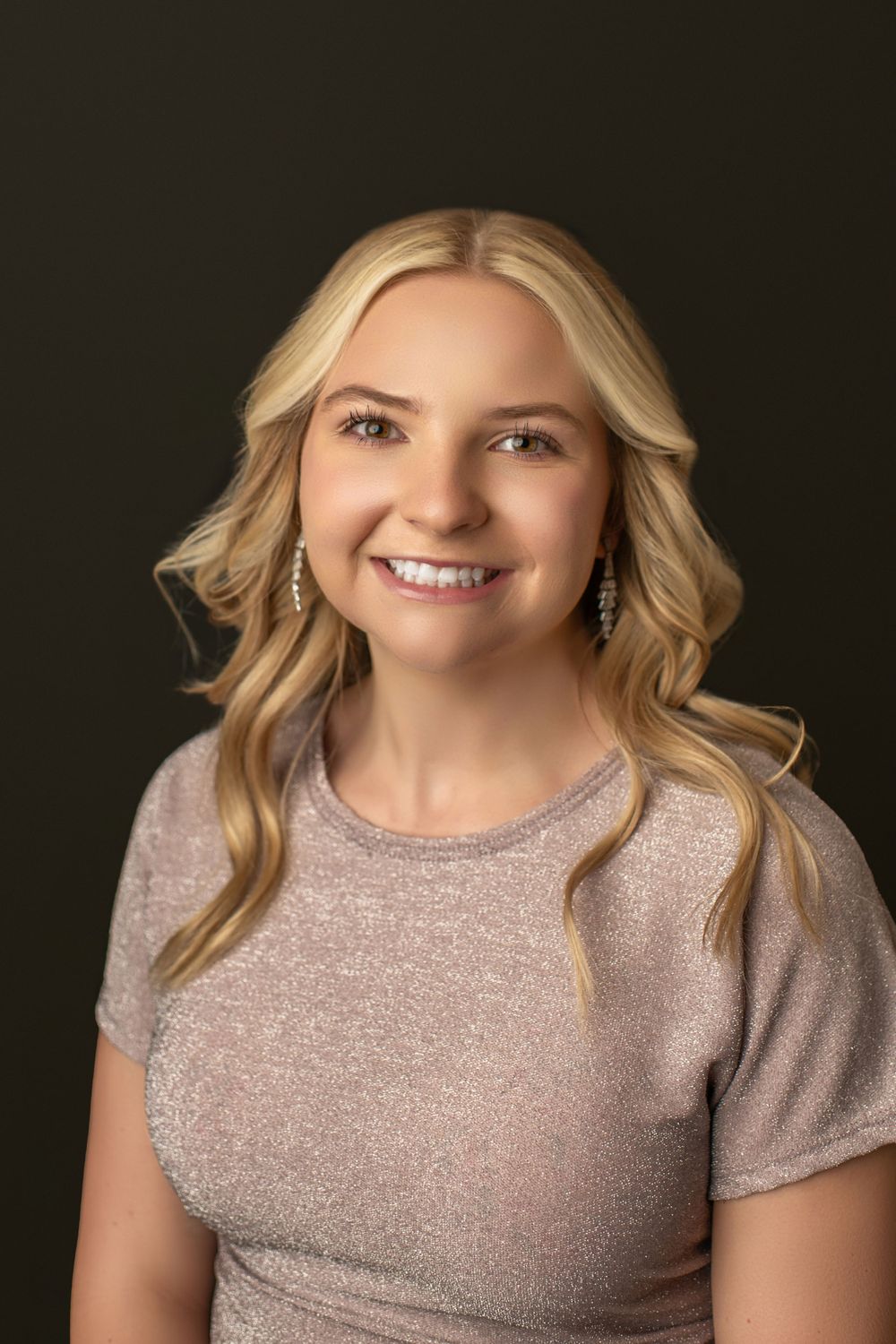 Studio portrait with dark green background and soft lighting.