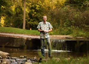 A scenic outdoor photo series near a waterfall with someone in casual attire.