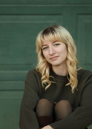 A cozy portrait in an olive sweater against a green background with soft lighting.