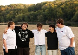 Group of friends laughing together outdoors with hills in the background.