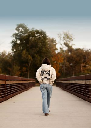 Walking away on bridge wearing Iowa sweatshirt showing back graphic design.