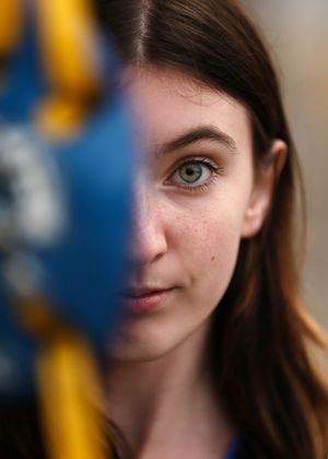 Close-up artistic portrait with dramatic lighting and vibrant blue background.