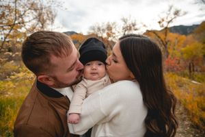 A family shares tender moments together against a backdrop of autumn foliage in the mountains.