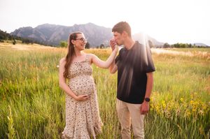 A couple sharing a romantic moment together in a golden sunlit meadow at sunset.