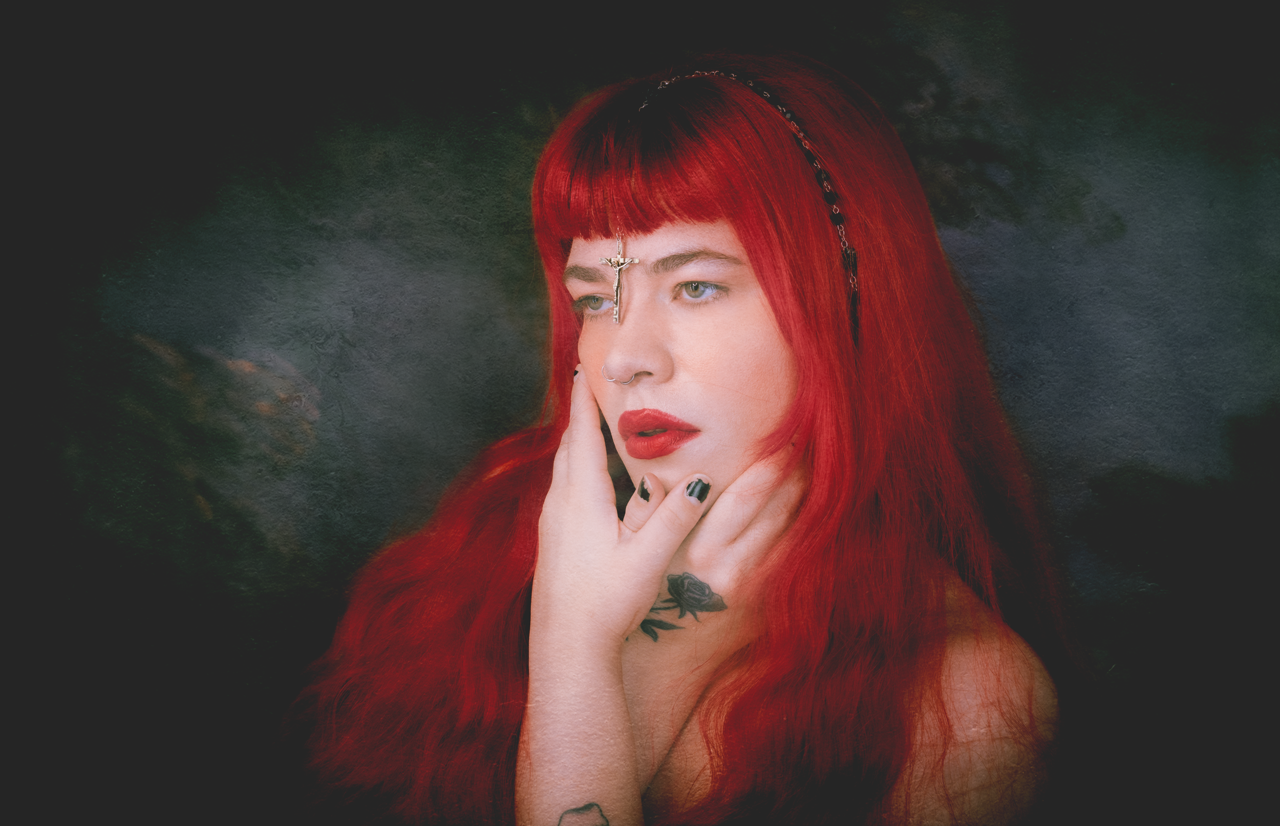 Dramatic portrait with vibrant red hair against dark moody background.