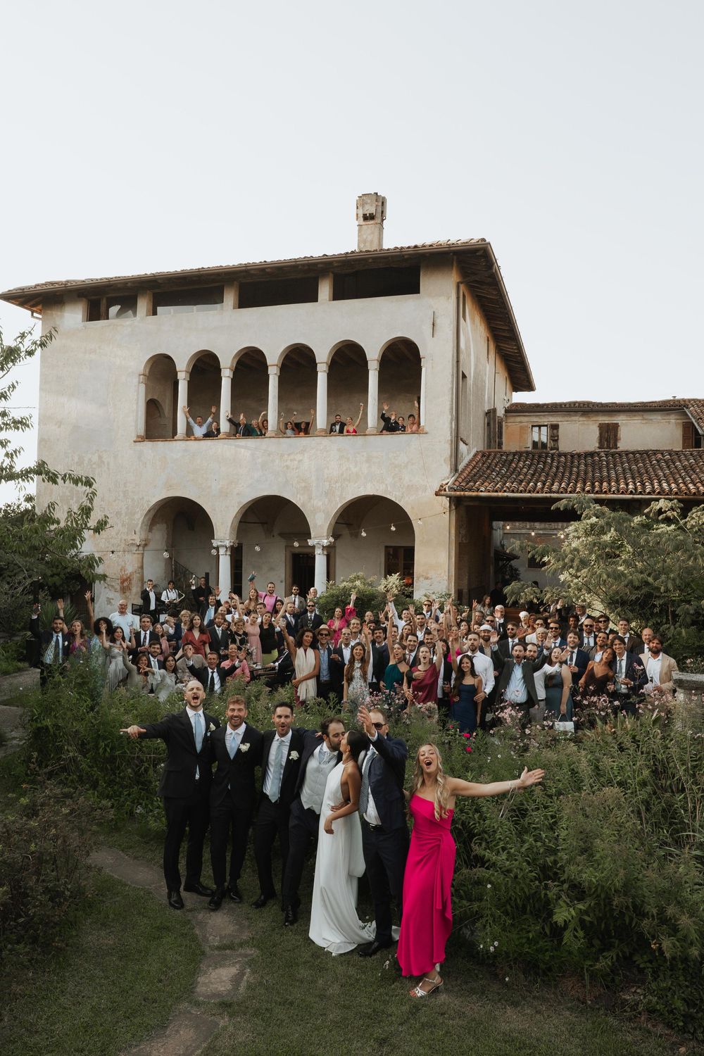 Large group of wedding guests gathered outside a Mediterranean-style villa.