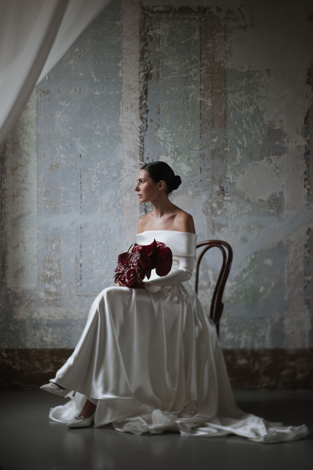 A white wedding gown and burgundy bouquet create an elegant bridal portrait.