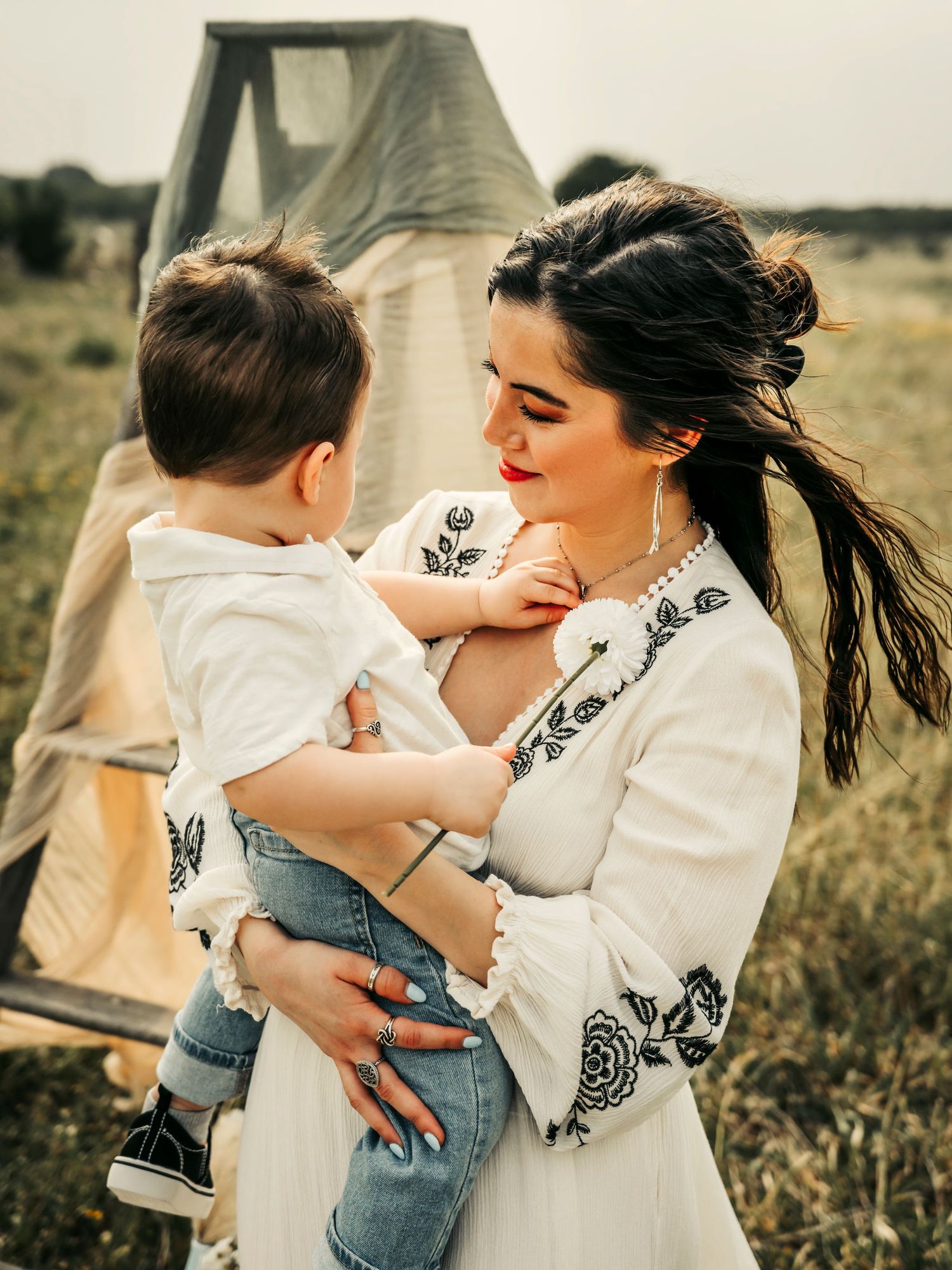 Mother and young son embracing in an open field, capturing a tender moment of love and connection.