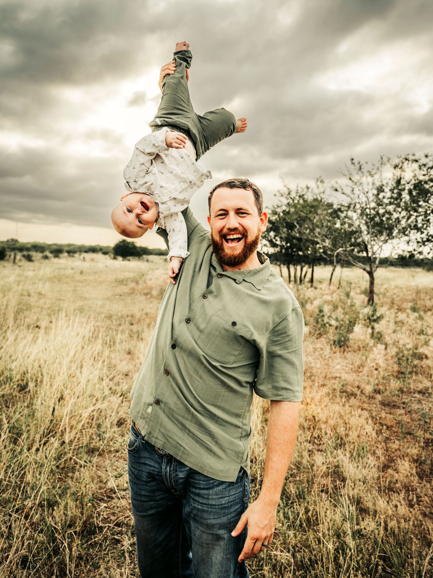 Father and young son playing and laughing together in the sunshine, capturing a joyful and carefree moment.